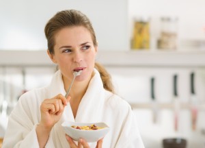 Happy Young Woman In Bathrobe Eating Healthy Breakfast